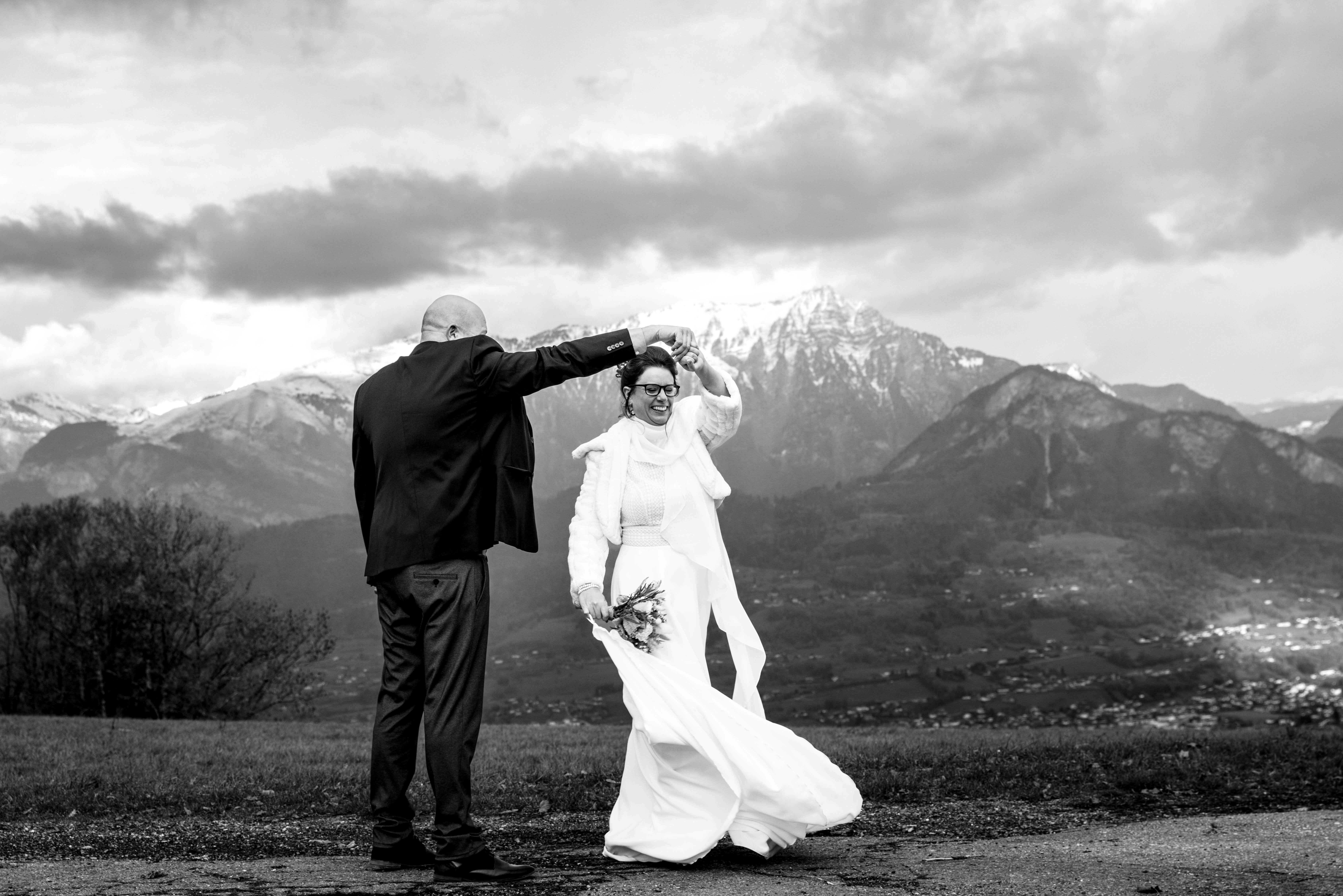 photo en noir et blanc de maries qui dansent devant la montagne
