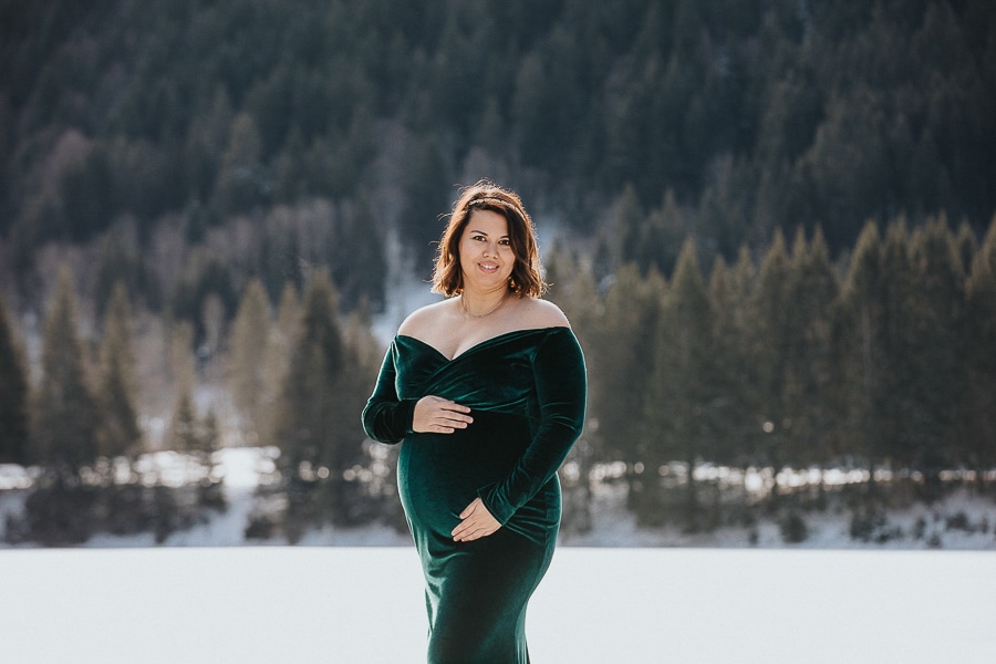 seance photo dans la neige en hiver avec une femme enceinte en robe verte à la montagne près de douvaine 
