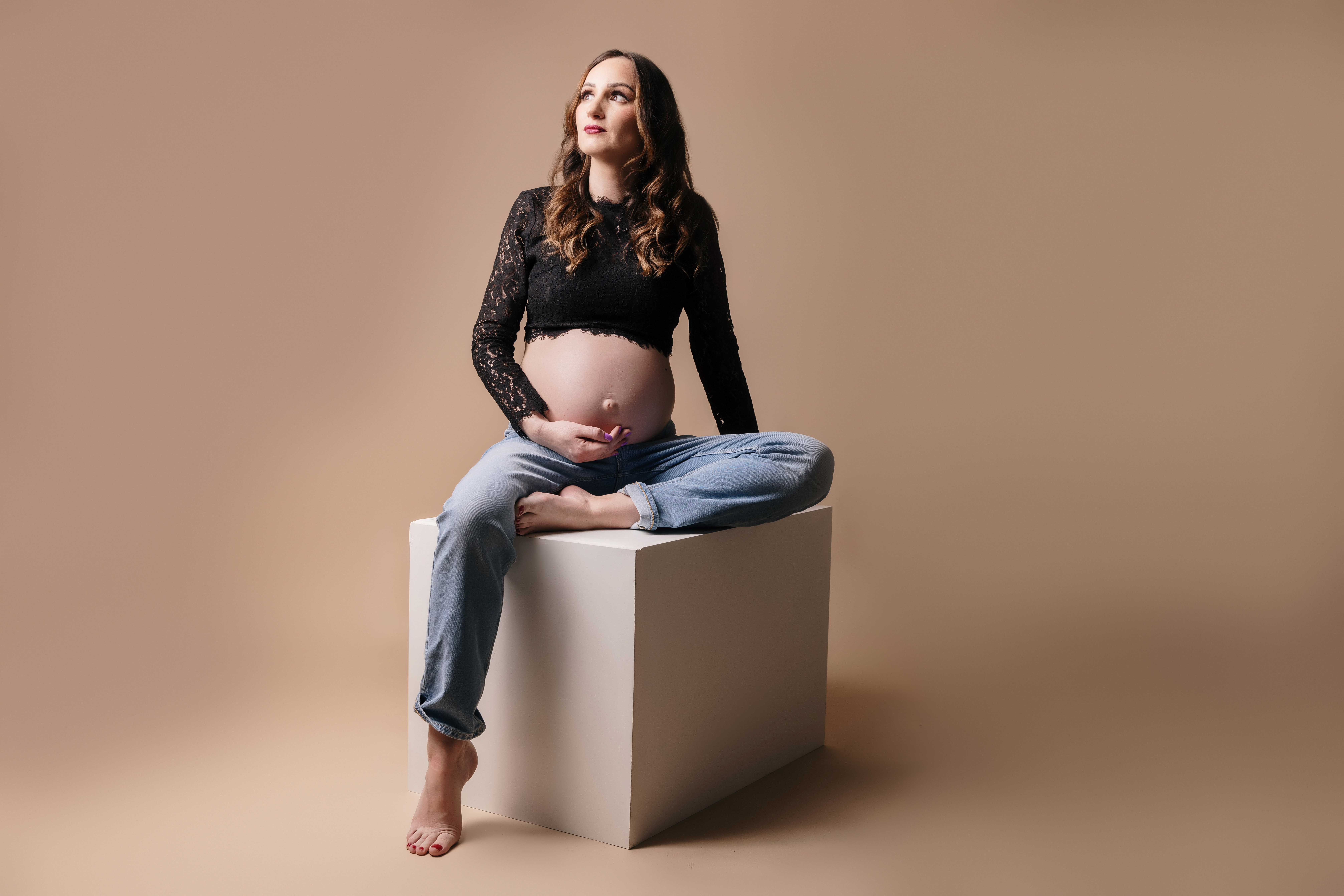 photo de femme enceinte en studio avec un fond clair et sur un cube